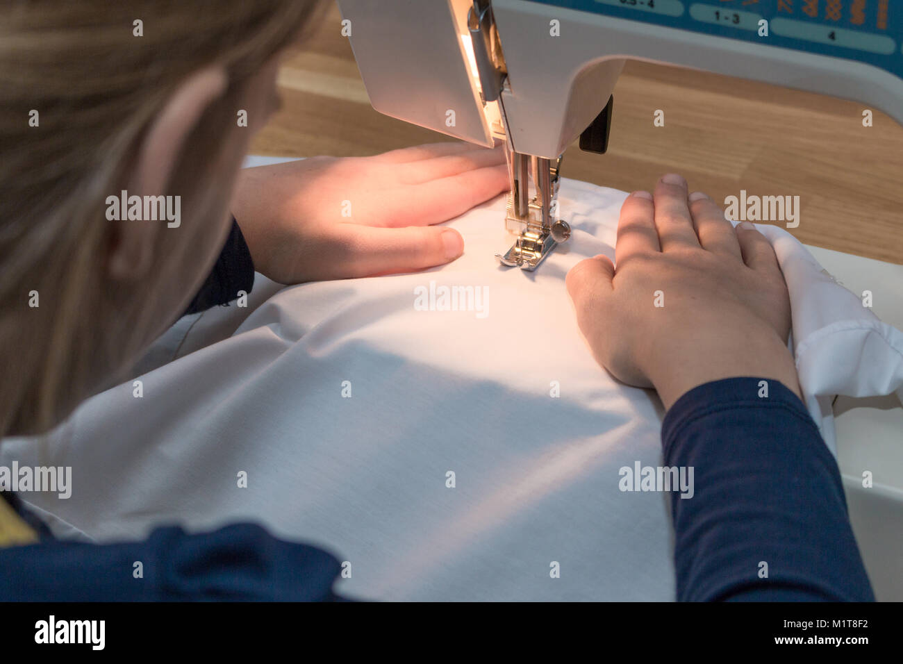 Une fillette de 8 ans est une couture textile blanc. Close-up Banque D'Images