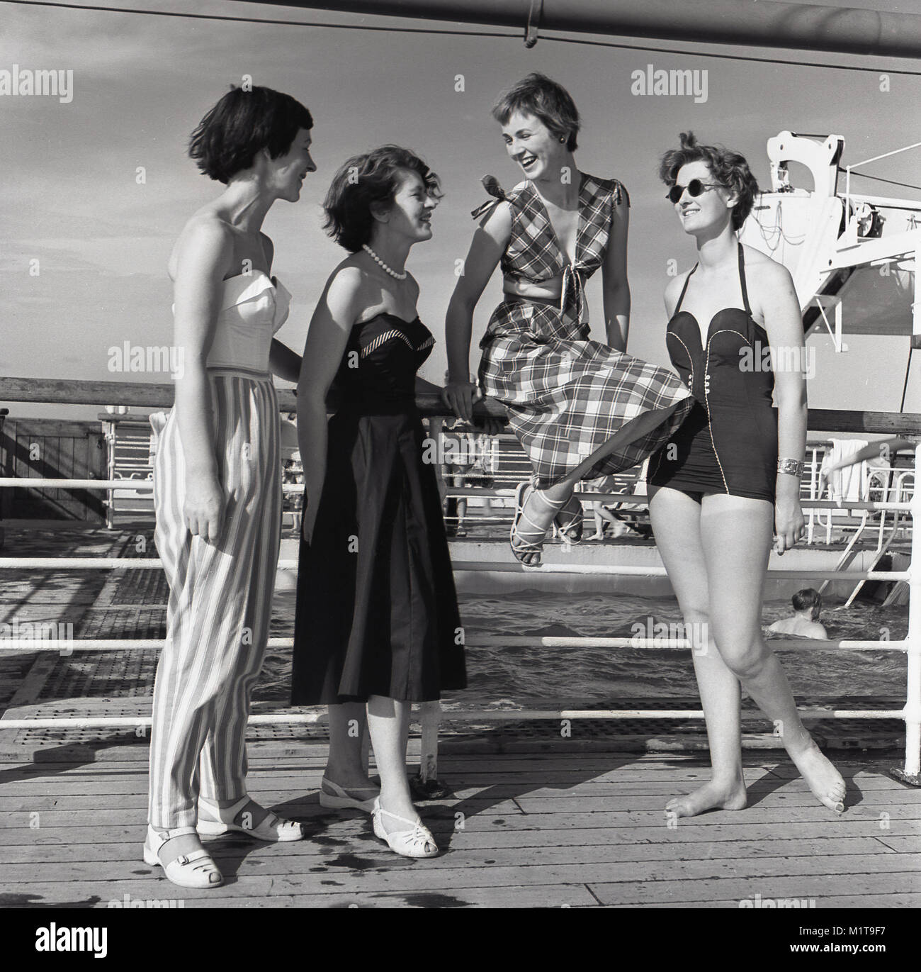 Années 1950, historique, à bord d'un bateau à vapeur Union-Castle en milieu de l'océan s'est dirigé vers la Cape en Afrique du Sud, quatre heureux, excité les jeunes femmes se tenir par le navire en piscine dans le garde-corps et de vêtements maillot de la journée. Banque D'Images