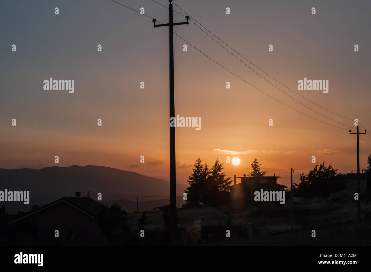 Poteaux électriques Le courant traversant la ligne contre un ciel clair au coucher du soleil à Oratino campagne, Campobasso, Molise, Italie. country house silhouette Banque D'Images