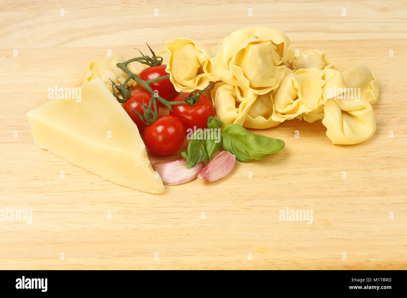 Tortelloni avec de l'ail, le basilic, tomates et fromage de brebis sur une planche à découper en bois Banque D'Images