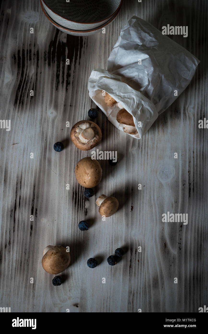 Photo verticale avec vue de dessus sur le brown des champignons comestibles à partir de sac de papier. Les champignons sont sur vintage bois blanc avec couleur et usés Banque D'Images