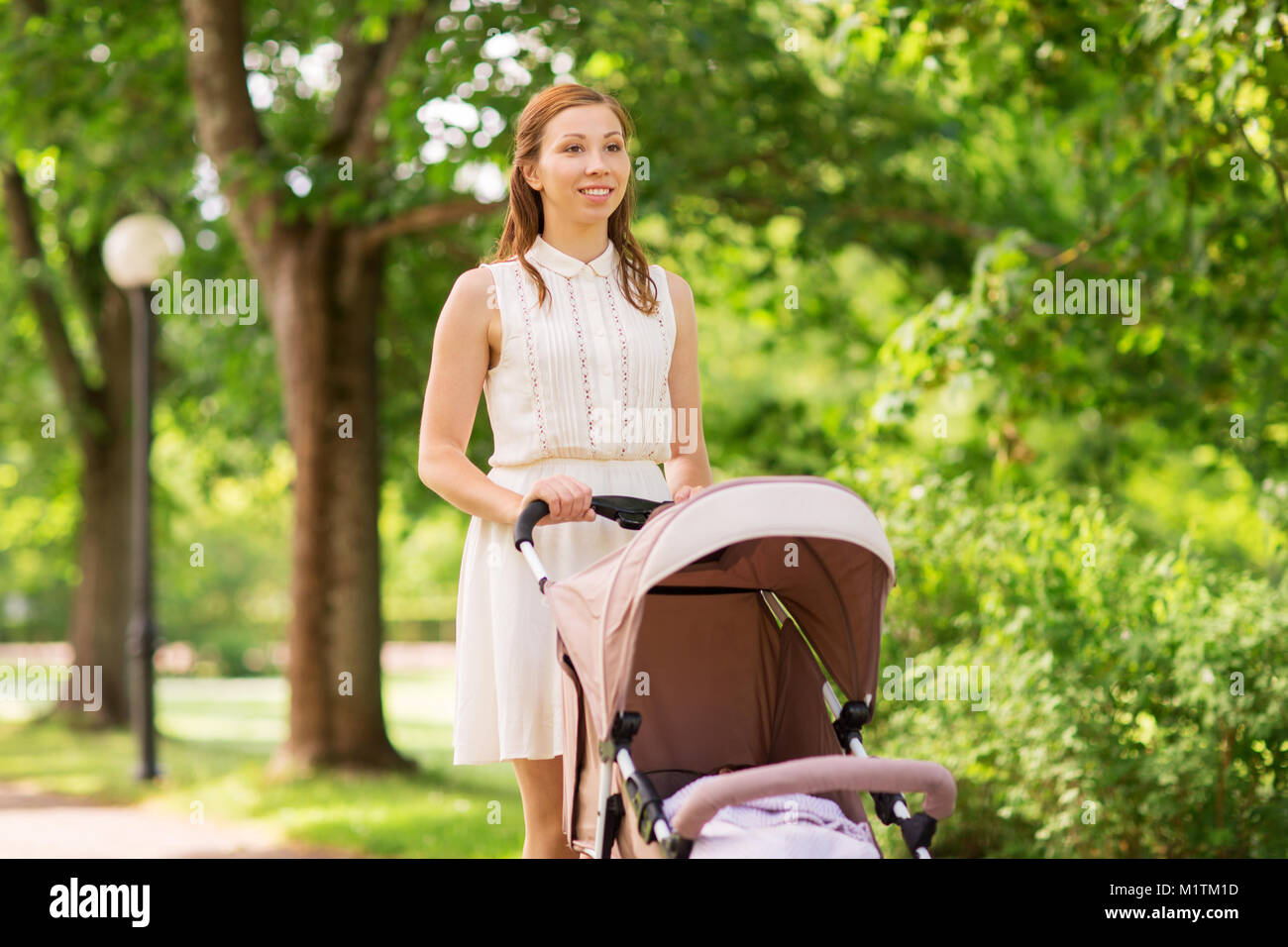 Heureuse Mère avec enfant en poussette au parc d'été Banque D'Images