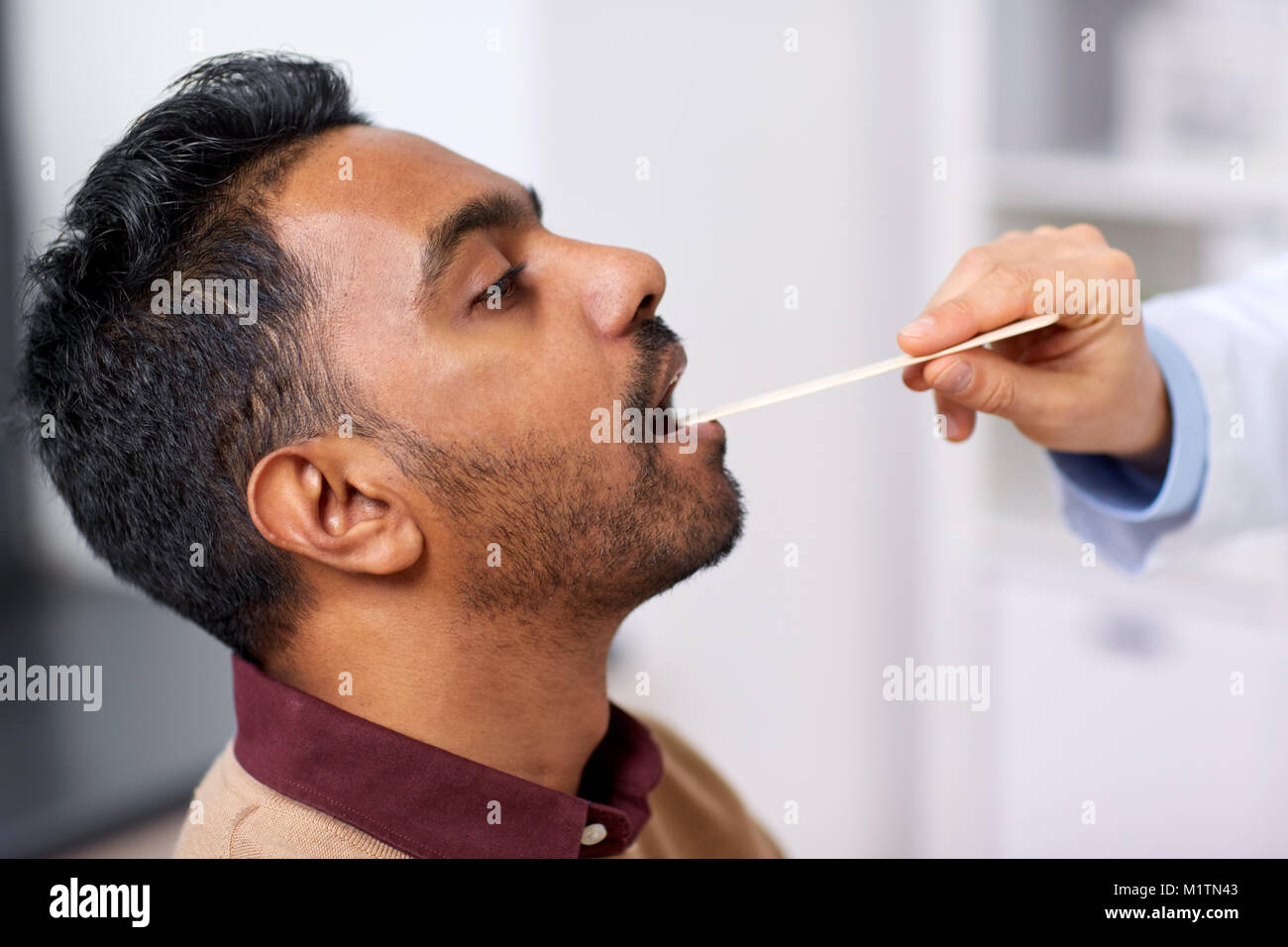 Par ailleurs médecin examinant la gorge du patient à la clinique Banque D'Images