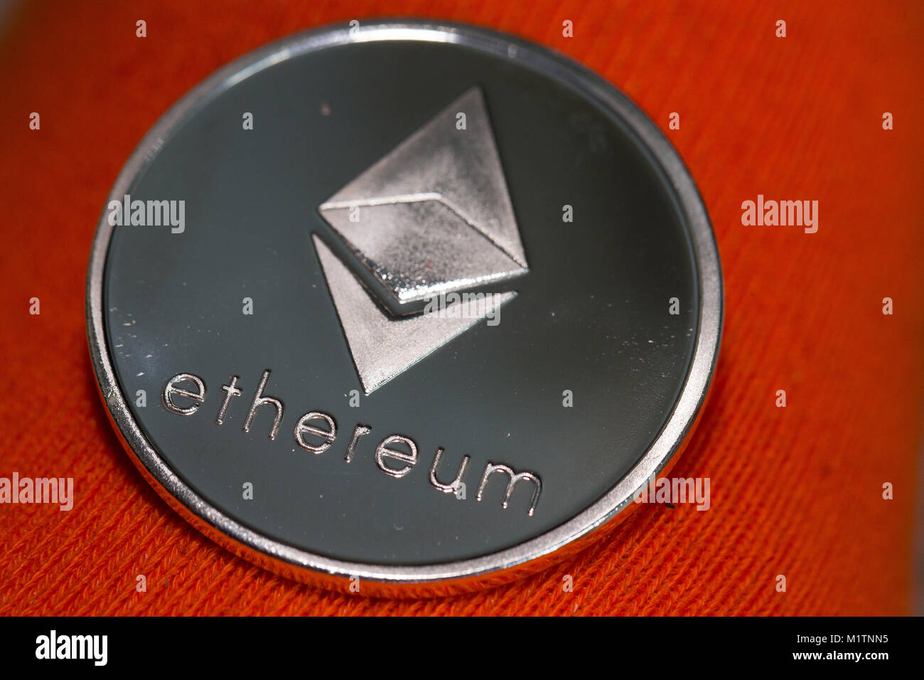 Un argent physique Ethereum (ETH) jeton pièce crypto sur fond orange Photo  Stock - Alamy