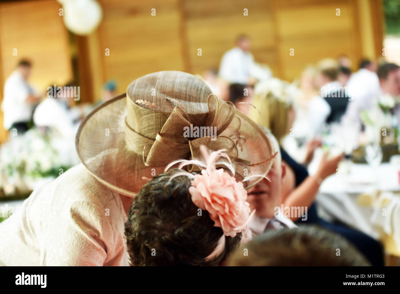 Mère de la mariée de porter un grand chapeau parle à un invité de mariage en privé à un mariage de famille Banque D'Images