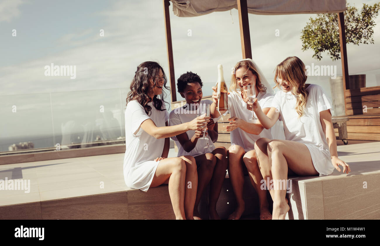 Happy young women drinking champagne at partie de bachelorette sur toit. Mariée de demoiselle d'honneur et s'amusant à hen party. Banque D'Images