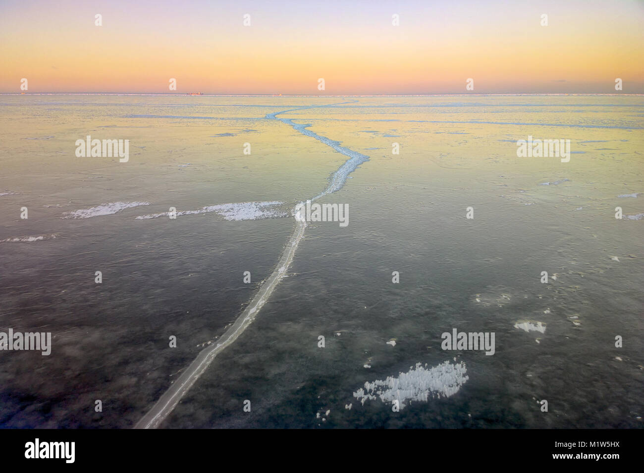 Jeune glace (nilas) à la baie d'eau douce de la mer Baltique, faible soleil d'hiver en contour, première fissure dans la glace, les cristaux de glace Banque D'Images