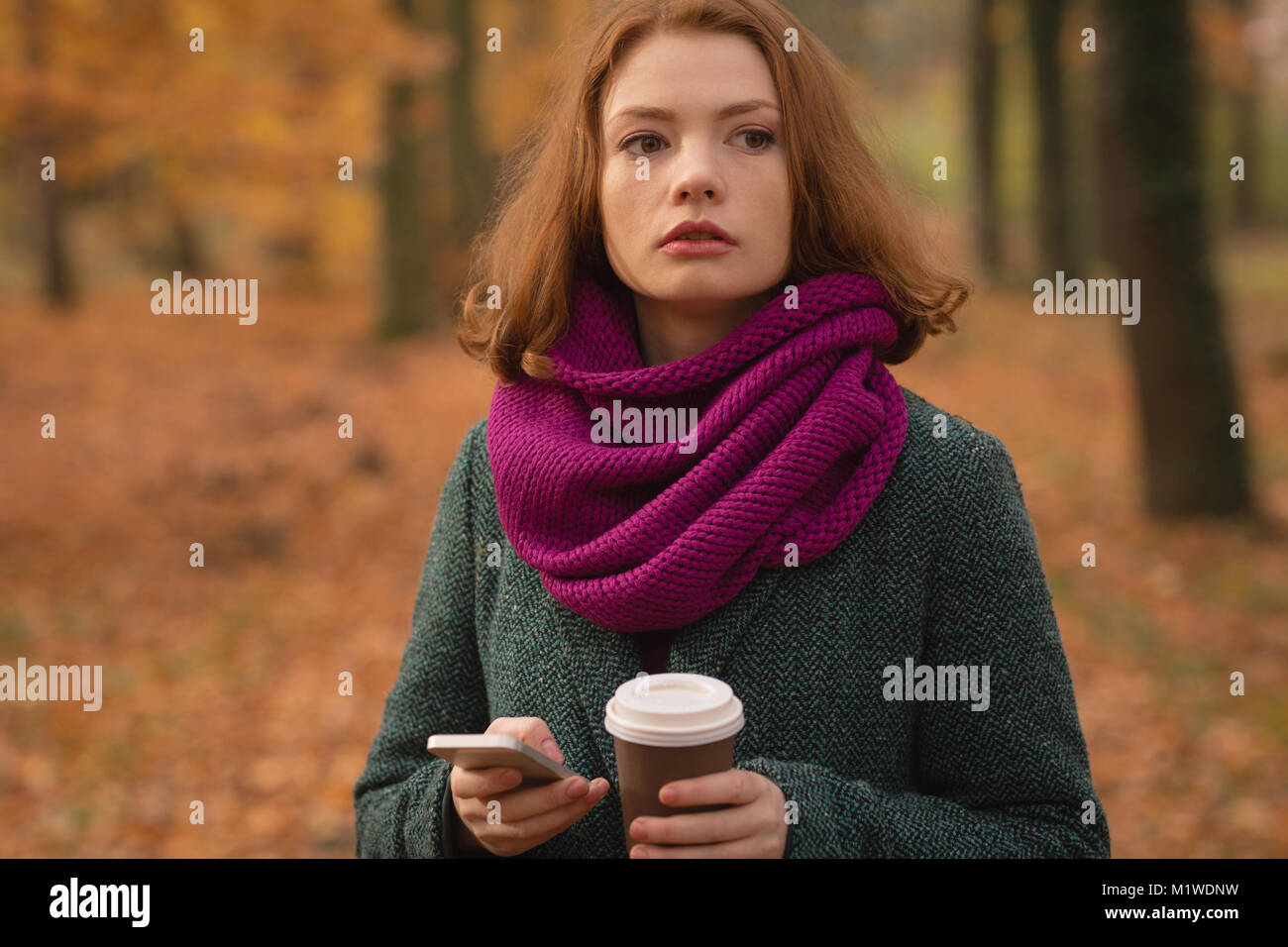 Woman using mobile phone while having coffee Banque D'Images