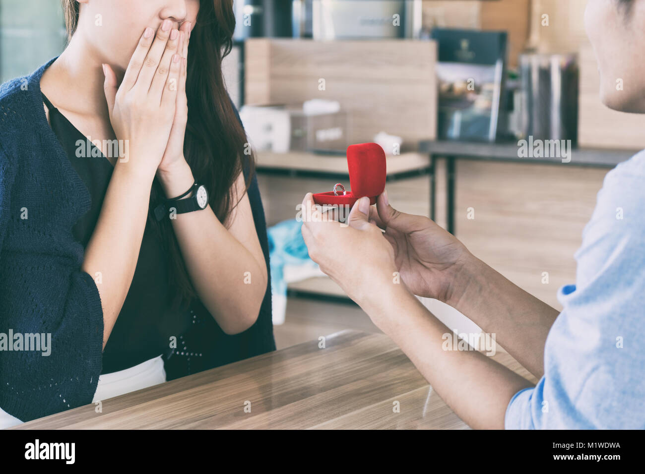 L'homme asiatique montrant une bague de fiançailles en diamant à sa petite amie dans un restaurant étonné avec un coucher du soleil chaleur piscine dans l'arrière-plan. Proposition concept Banque D'Images