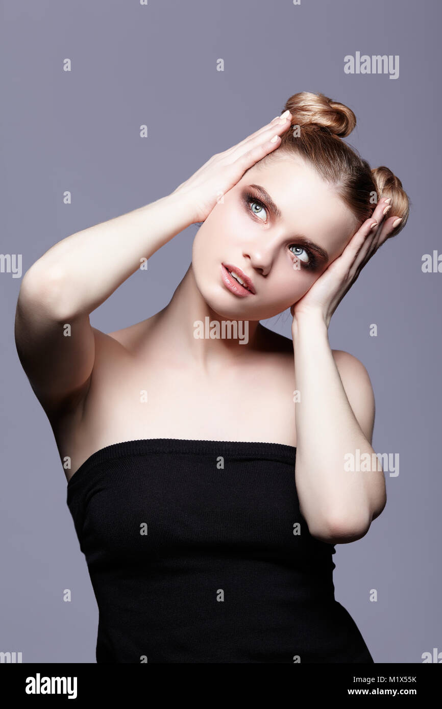 Les jeunes femmes de l'adolescence avec portrait de beauté maquillage jour et bun hair style sur fond gris Banque D'Images