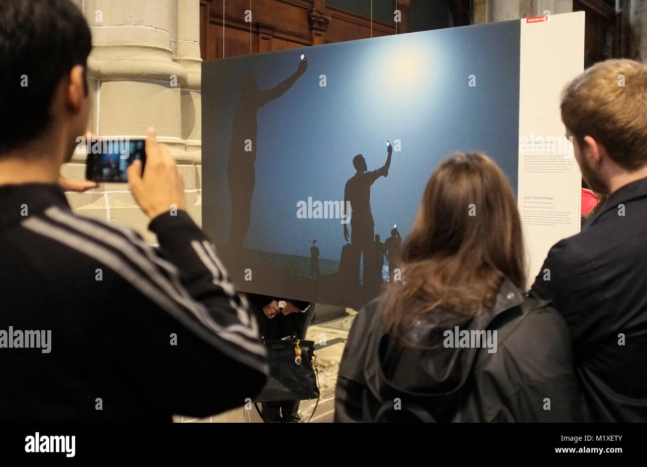 Les visiteurs de 2014 World Press Photo exhibition in De Nieuwe Kerk, Amsterdam, photo et lisez à propos de l'image gagnante par John Stanmeyer. Banque D'Images