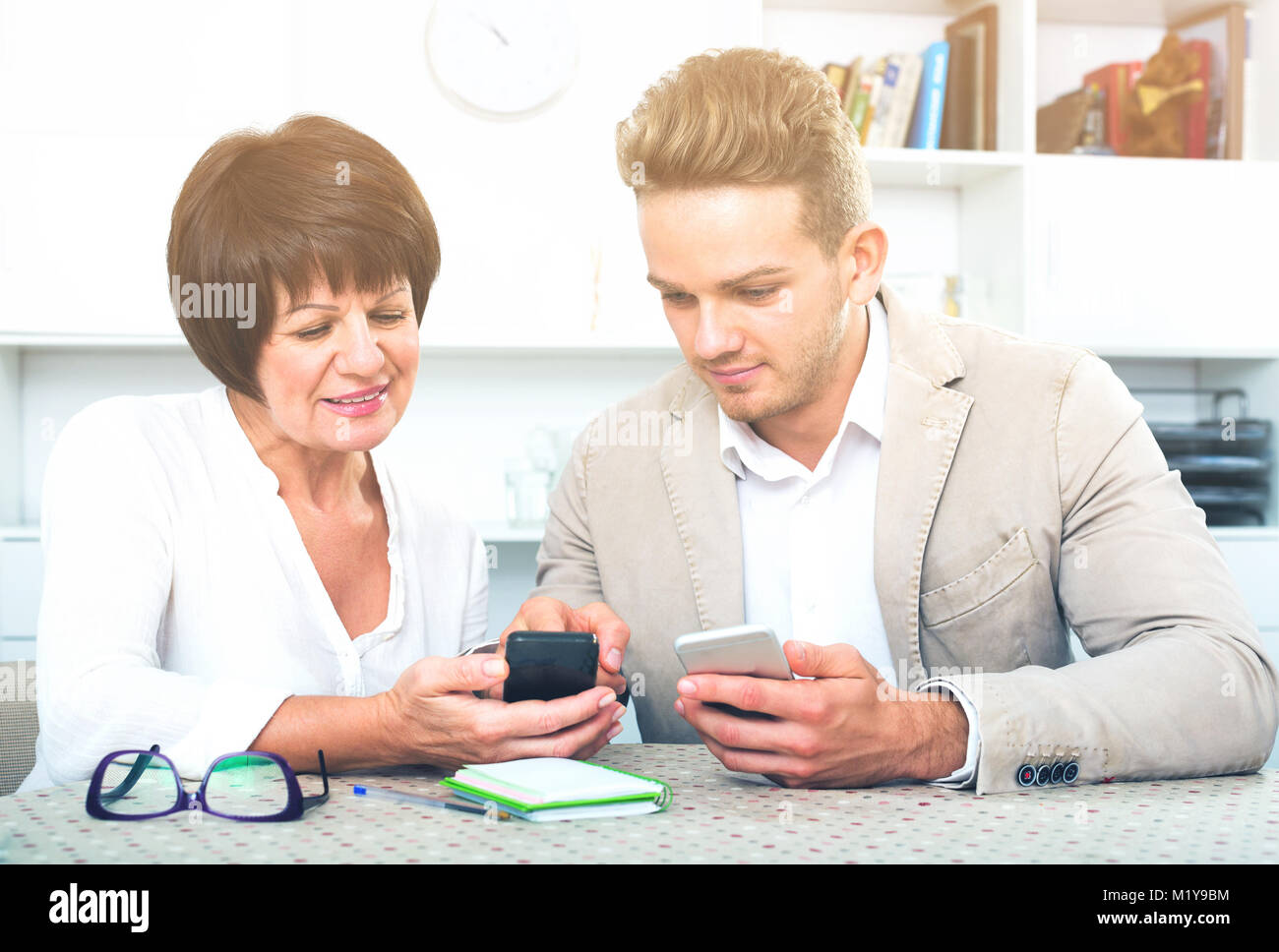 Mère âgée avec son jeune fils à étudier de nouvelles fonctions des smartphones Banque D'Images