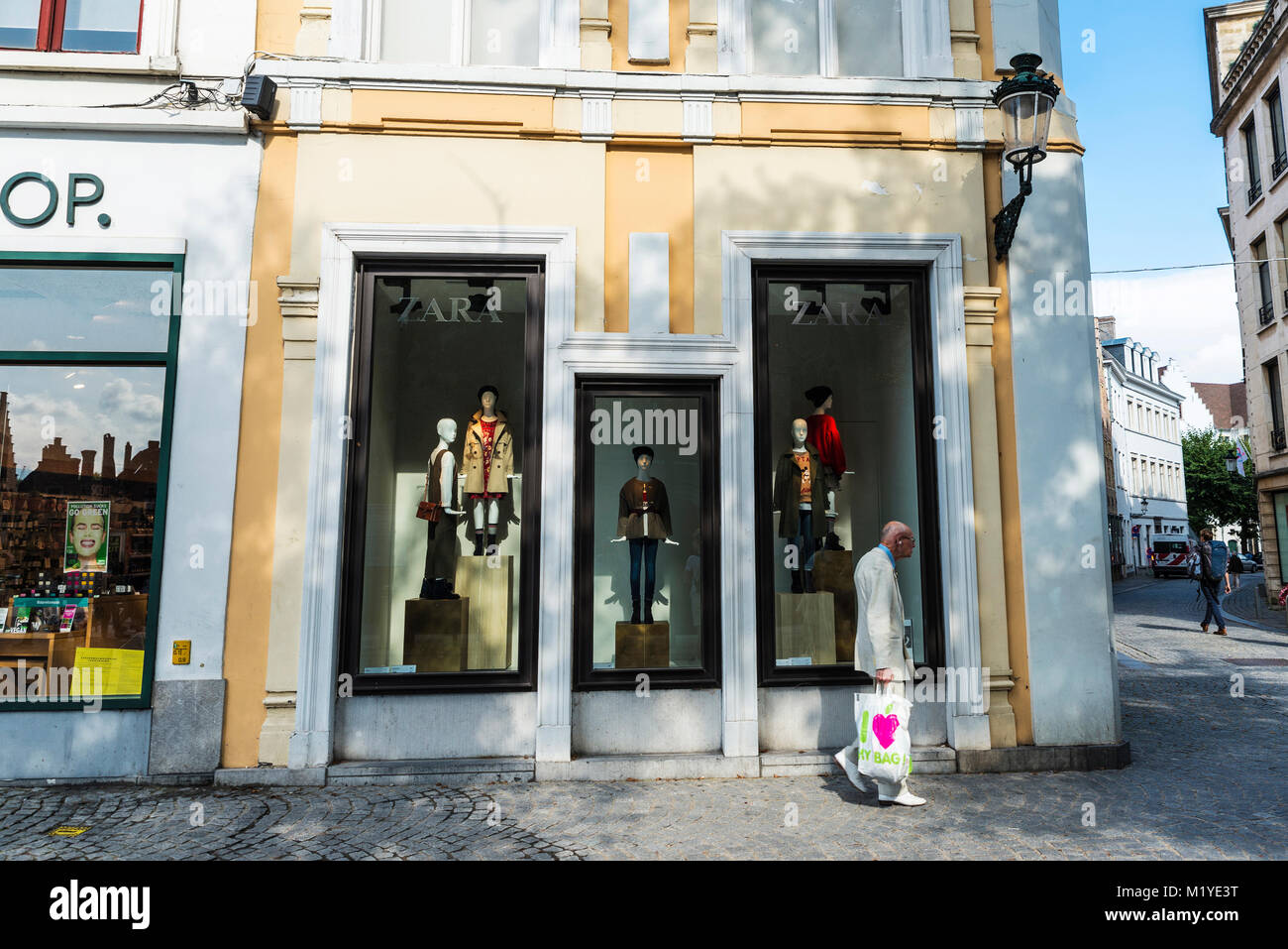 Bruges, Belgique - 1 septembre 2017 : Vieil homme en costume blanc marchant devant une boutique Zara pour les enfants dans la ville médiévale de Bruges, Belgique Banque D'Images