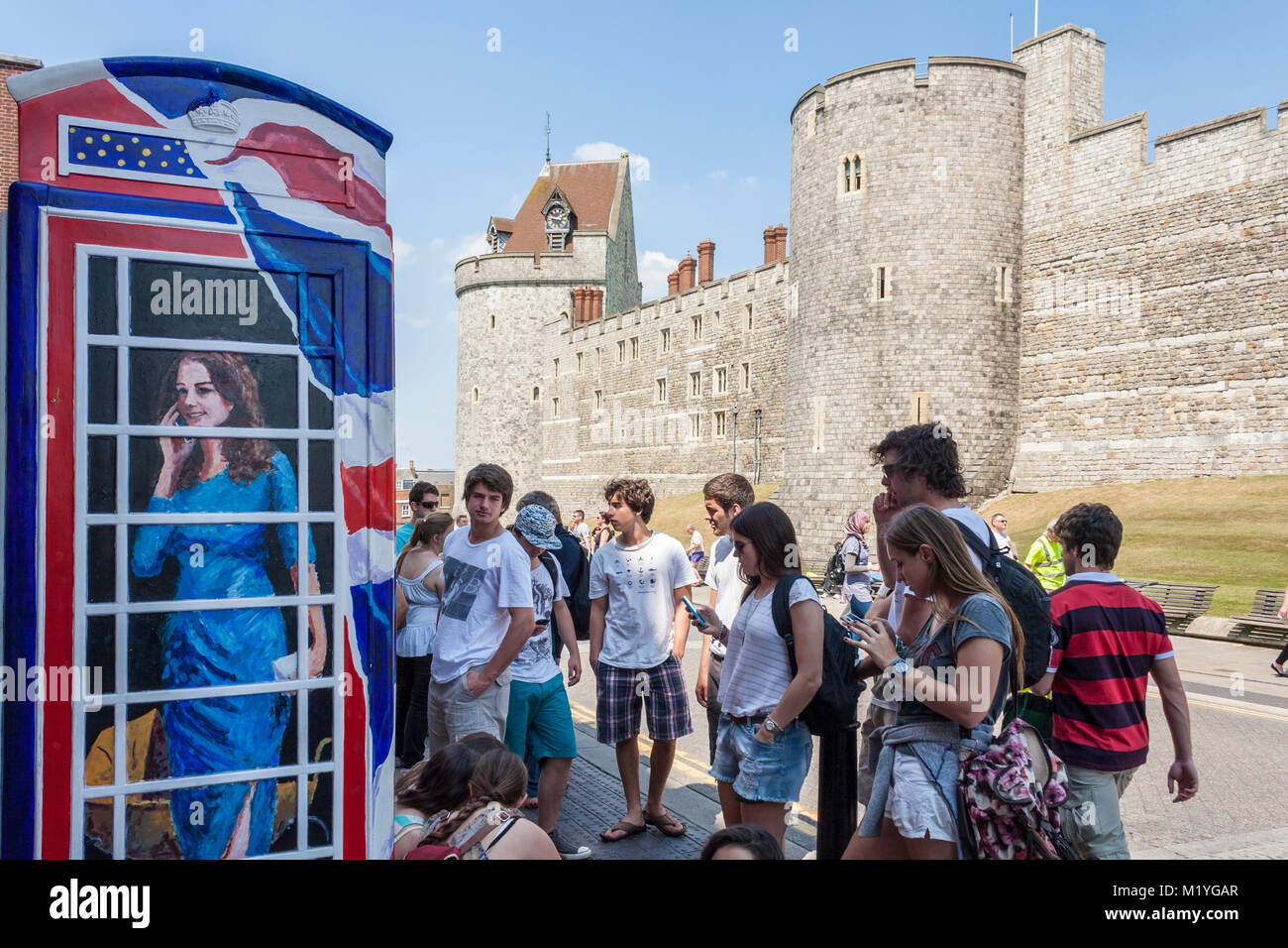 Les touristes regarder les téléphones portables à l'extérieur d'un téléphone traditionnel fort peint avec un portrait de Kate Middleton, duchesse de Cambridge, parler Banque D'Images