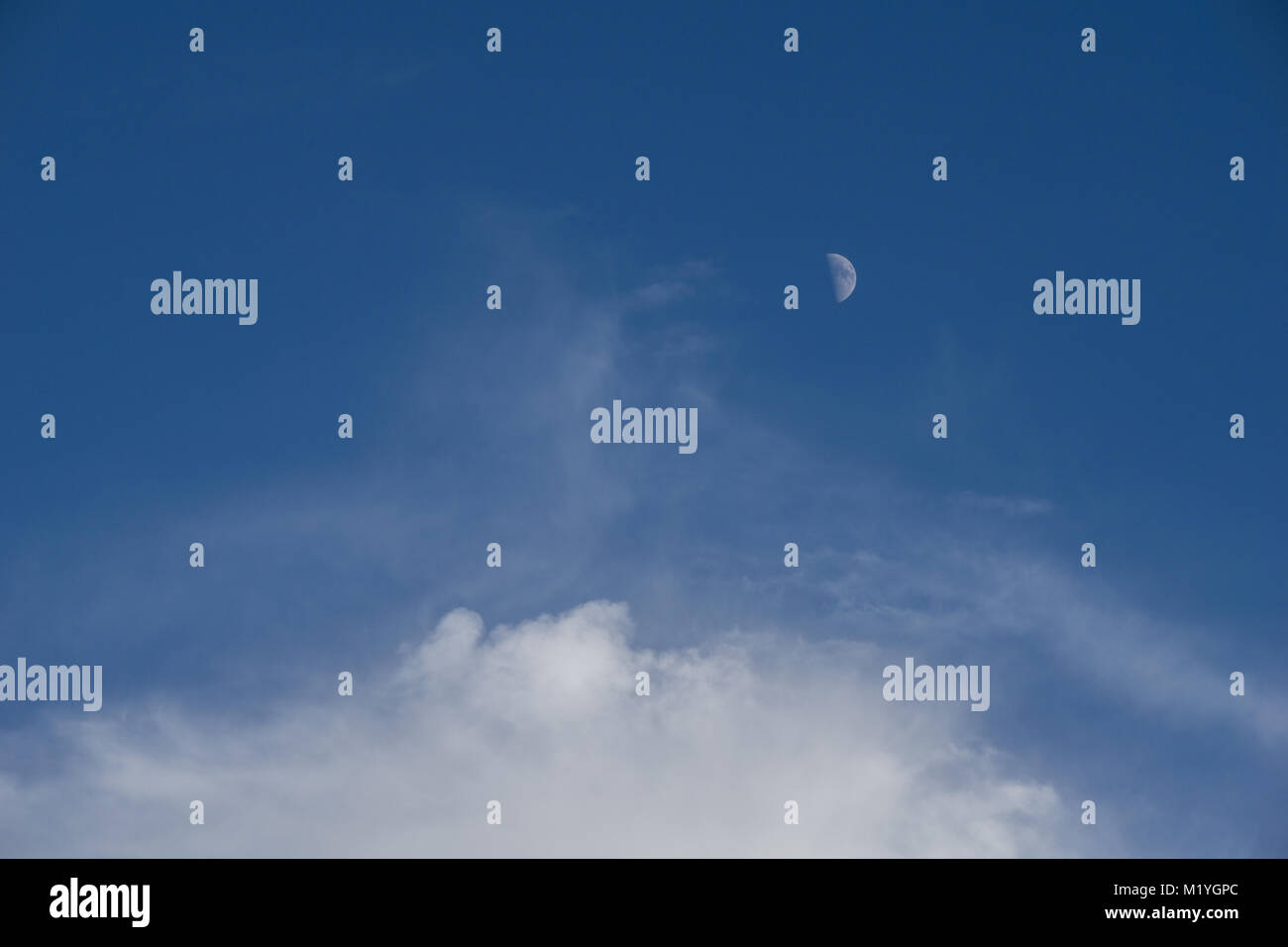 La lune au milieu de la journée et les nuages blancs moelleux Banque D'Images