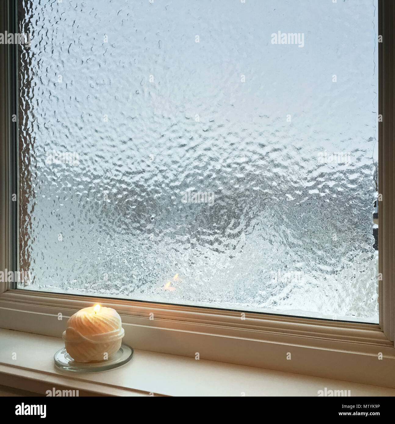 La combustion de la bougie près de la fenêtre givrée. Météo après la pluie  verglaçante Photo Stock - Alamy