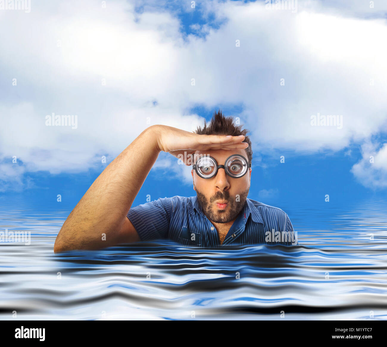 Homme avec expression drole et verres épais à très loin dans l'eau de la mer. Banque D'Images