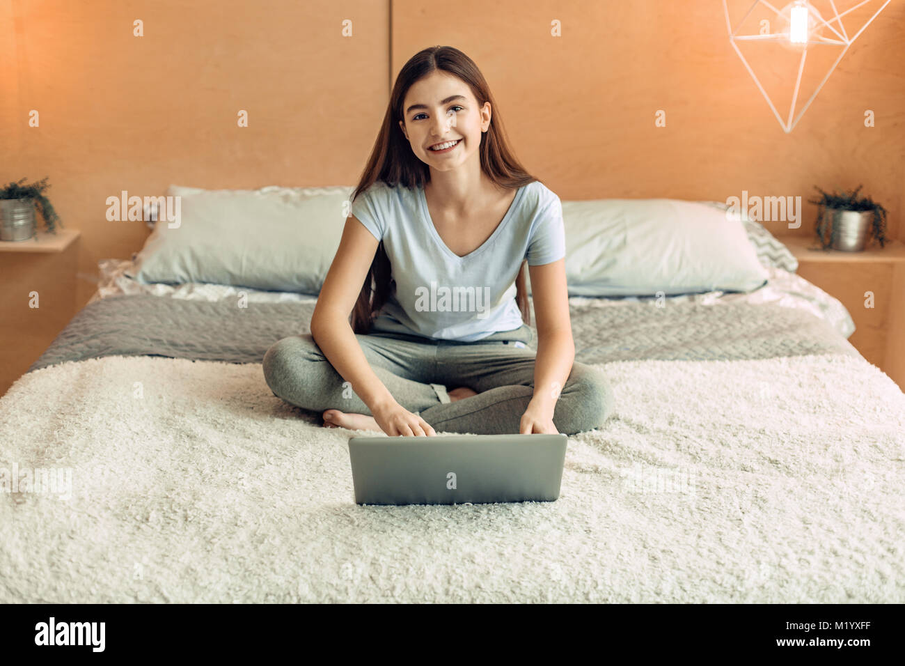 Adorable teenage girl smiling while using her laptop Banque D'Images