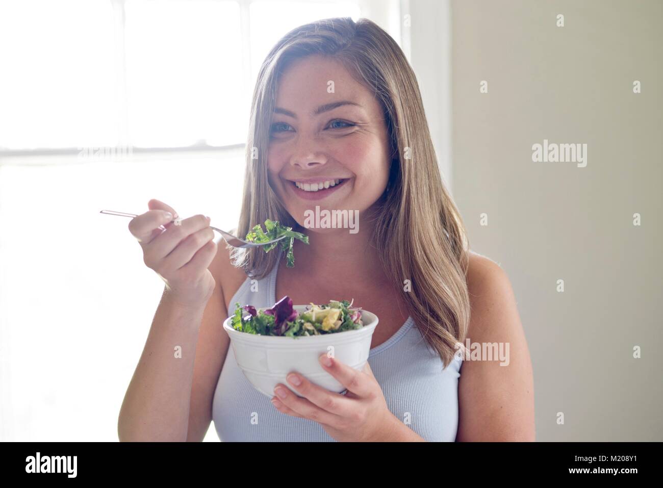 Portrait of young woman eating salad. Banque D'Images
