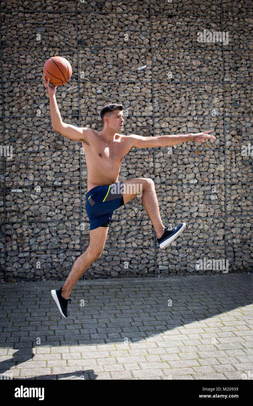 Jeune homme sautant avec le basket-ball. Banque D'Images