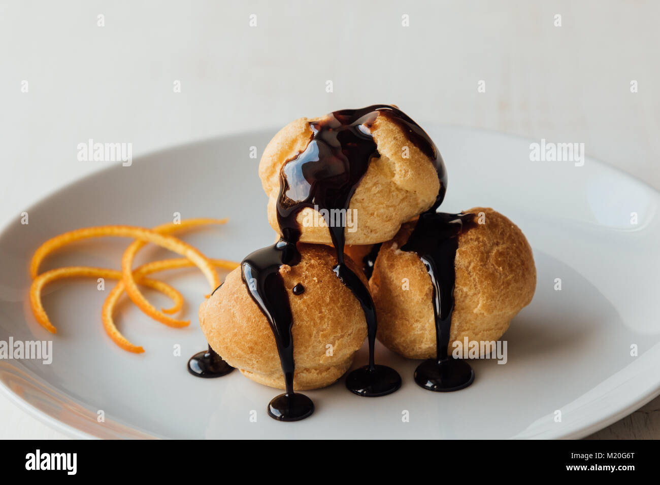 Profiteroles à la crème et savoureux lustre de chocolat sur une plaque Banque D'Images