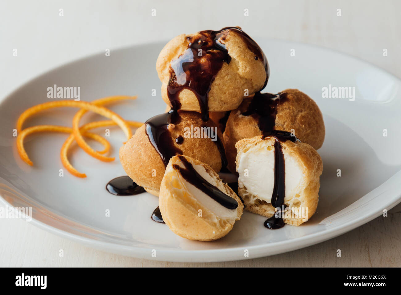 Profiteroles à la crème et savoureux lustre de chocolat sur une plaque Banque D'Images