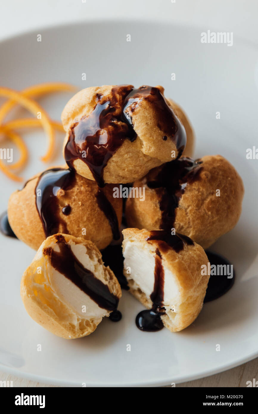 Profiteroles à la crème et savoureux lustre de chocolat sur une plaque Banque D'Images