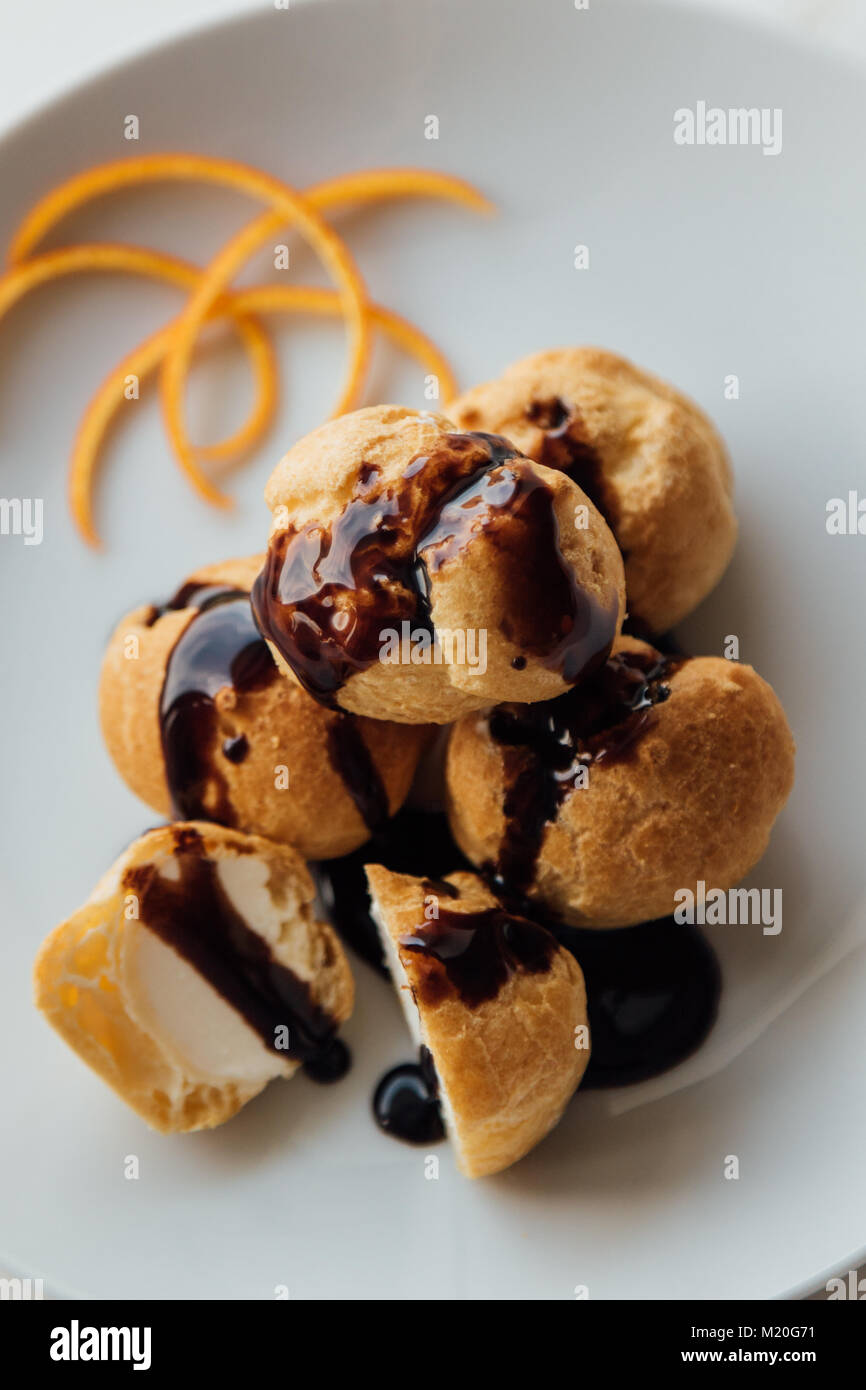 Profiteroles à la crème et savoureux lustre de chocolat sur une plaque Banque D'Images