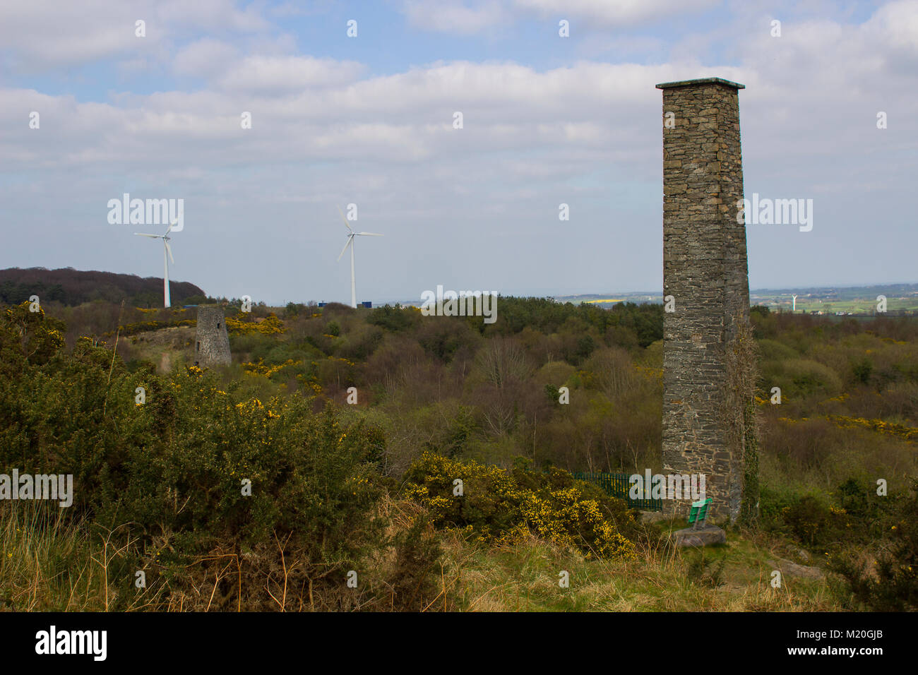 Une vieille cheminée industrielle avec des éoliennes modernes en arrière-plan sur l'ancien site des mines de plomb à Whitespots dans le comté de Down en Irlande du Nord Banque D'Images