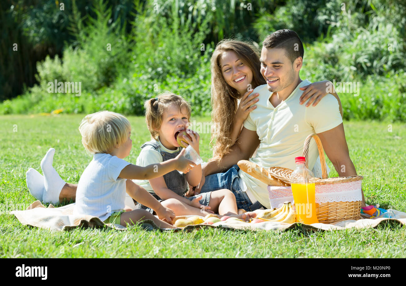 Smiling family de quatre sur pique-nique au parc, au jour d'été. Se concentrer sur la fille Banque D'Images