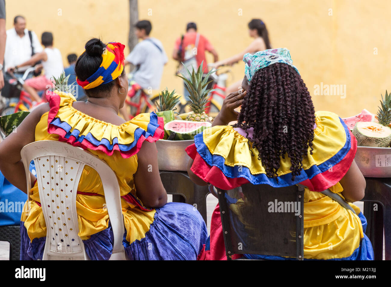 Cartagena, Colombie - Janvier 23th, 2018 : vue arrière de deux palenqueras vente de fruits frais tropicaux assis à la Plaza de San Pedro Claver en attente de cli Banque D'Images