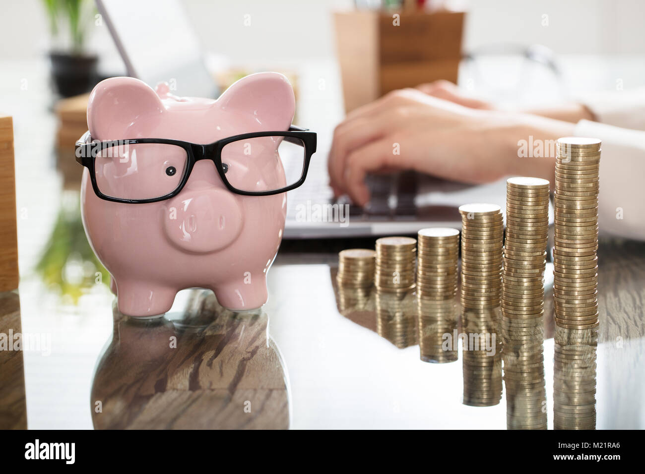 Tirelire et l'augmentation des crédits de la pile avant d'une personne à l'aide d'ordinateur portable sur le lieu de travail Banque D'Images