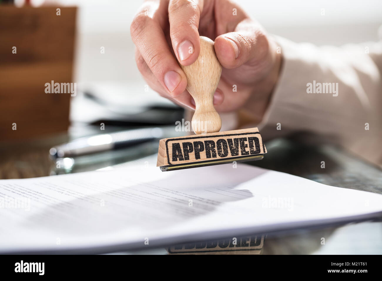 Close-up of a person holding a approuvé le Document sur l'horodateur sur Desk In Office Banque D'Images