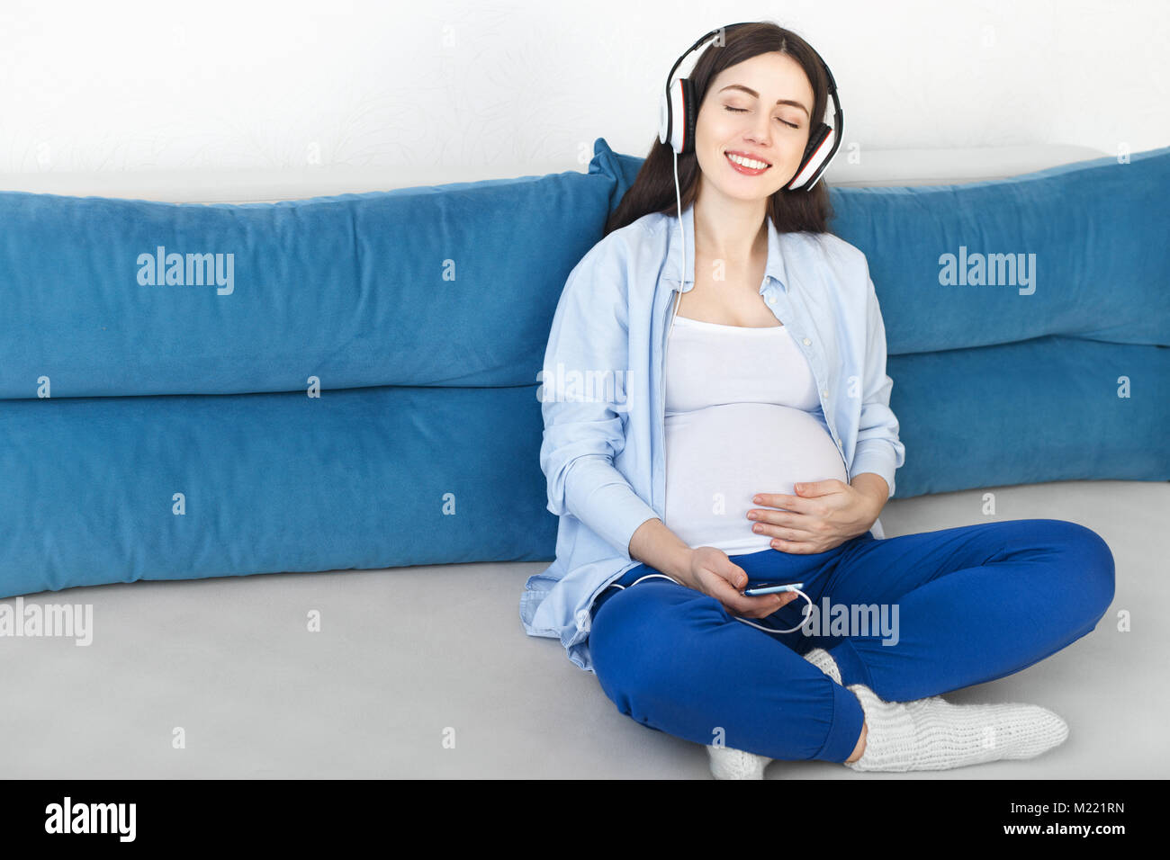 Femme enceinte l'écoute au casque de la musique Banque D'Images