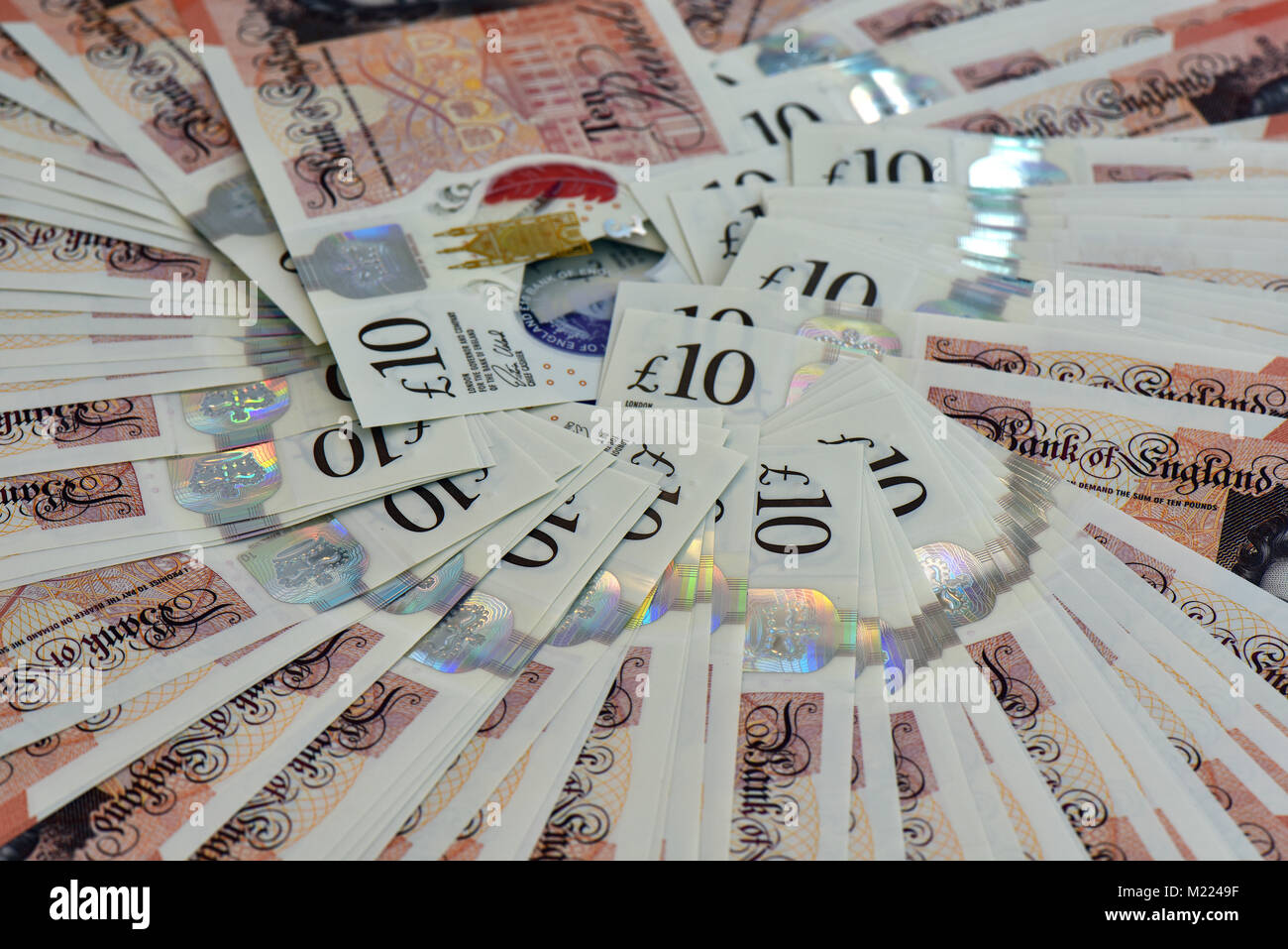 10 livres notes dans une forme d'éventail pose à plat sur une table ou une surface. Beaucoup de billets de banque de l'argent comptant et de l'épargne de nouveaux billets de banque style tenners ina ventilateur. Banque D'Images