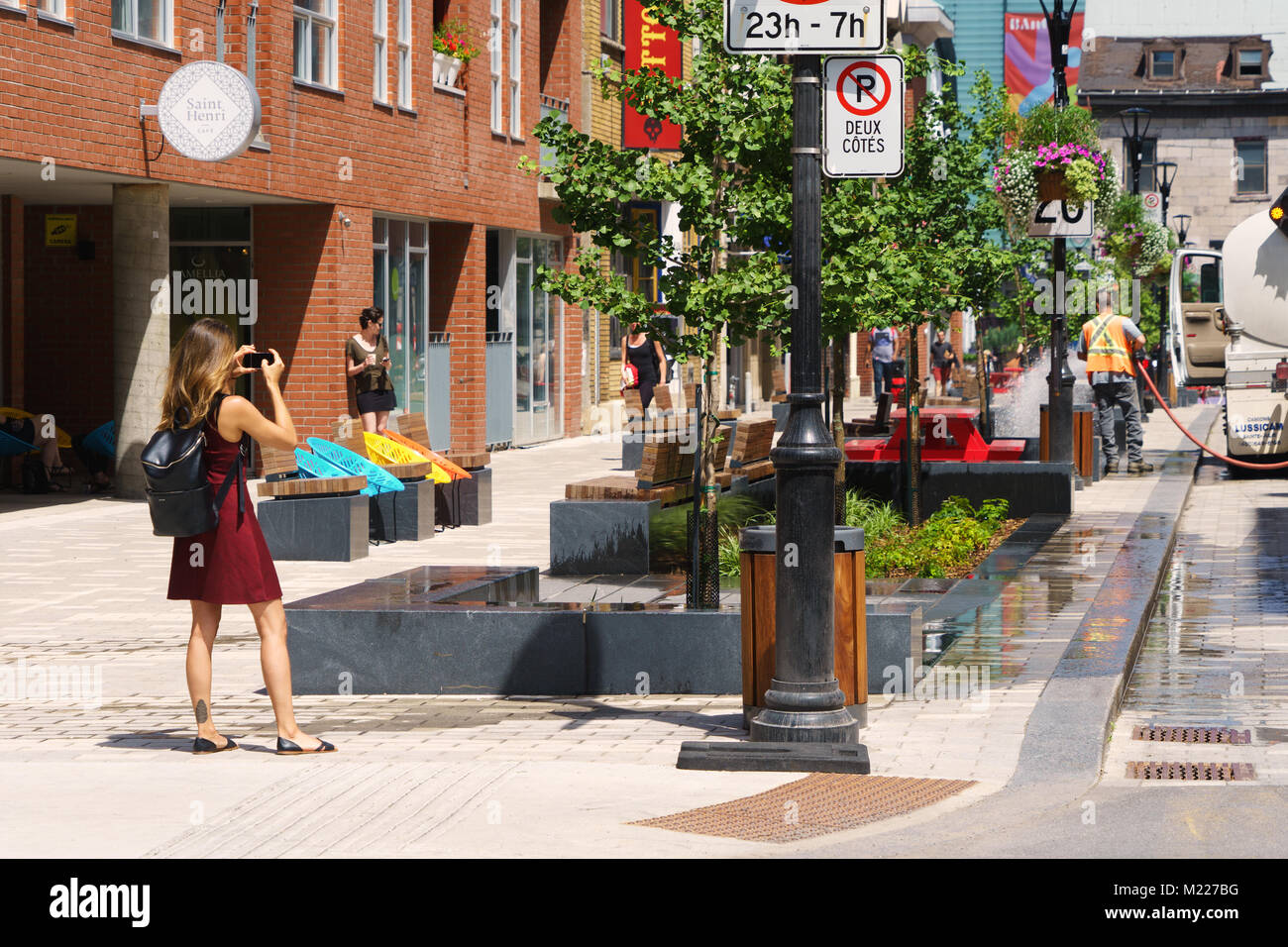 Jeune femme de prendre une photo avec son téléphone intelligent sur Emery street, Montréal, province de Québec, Canada. Banque D'Images