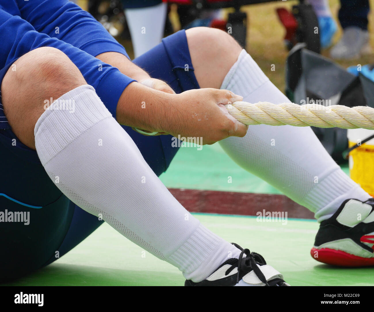 L'homme en tenue de sport bleu participant au remorqueur de la guerre le sport. L'accent principal sur ses mains avec du sable sur eux, tout en se préparant à lancer la corde de traction, essayant h Banque D'Images