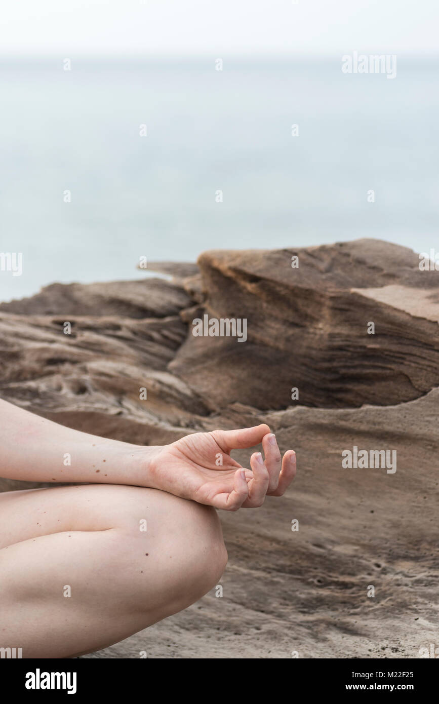 Méditer sur la plage avec le coucher du soleil dans l'arrière-plan Banque D'Images