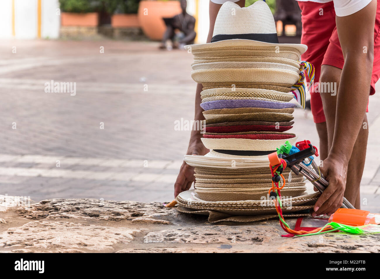 Un mâle hat vendeur laissant un tas de chapeaux de style colombien sur la rue à la Plaza de San Pedro Claver à Cartagena, Colombie. Banque D'Images