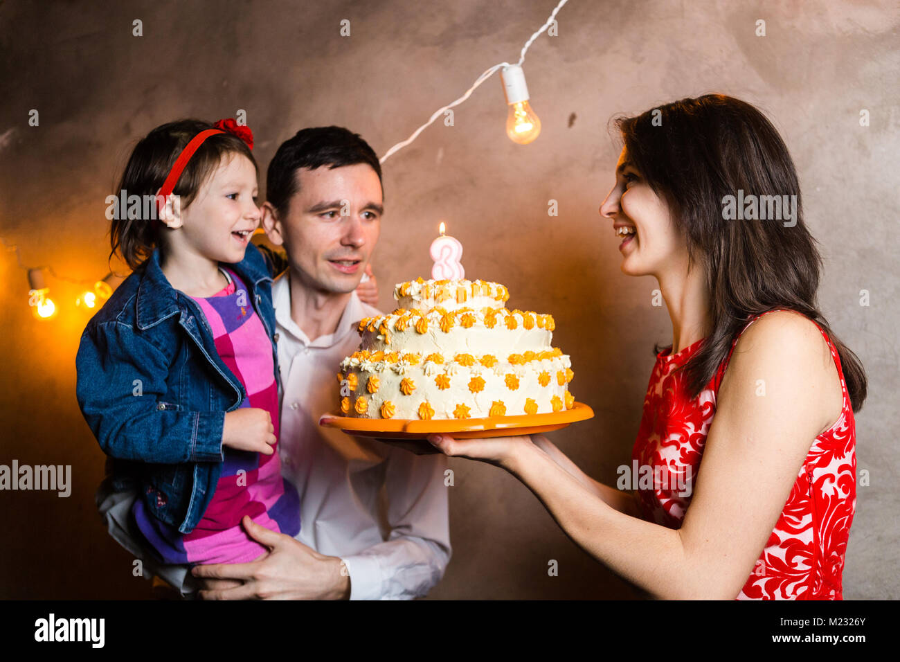 Maison De Famille Theme D Anniversaire Pour Enfants Et Blowing Out Candles On Grand Gateau Jeune Famille De Trois Personnes Debout Et Tenant Ma Fille De 5 Ans Je Photo Stock Alamy