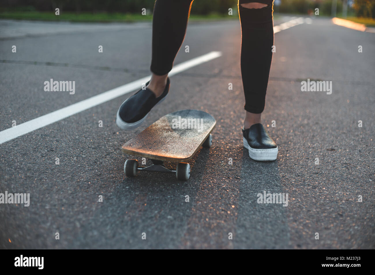 Jeune skateur professionnel jambes équitation sur planche devant le soleil Banque D'Images