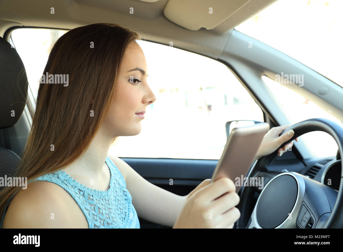 Vue latérale du portrait d'un conducteur distrait la lecture de message téléphonique au volant d'une voiture Banque D'Images