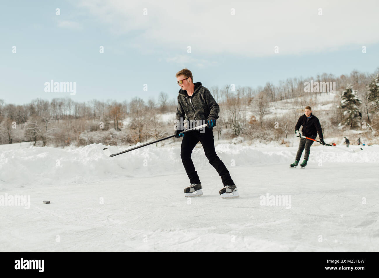 Deux hommes jouer au hockey sur glace sur un lac gelé Banque D'Images