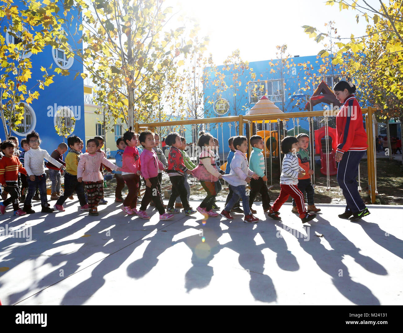 (180204) -- BEIJING, 4 février 2018 (Xinhua) -- un enseignant prend les enfants pour une après-midi de marche à une nouvelle école maternelle publique dans Gaimai Village de Yining County, nord-ouest de la Chine, la Région autonome du Xinjiang Uygur, Novembre 22, 2017. Le jardin de 800 mètres carrés peut accueillir plus de 300 enfants du village, il offre gratuitement au long de l'éducation avec des aliments et boissons. Yuanmin Li, un délégué à la 19e Congrès national du Parti communiste chinois (PCC), a servi comme secrétaire du parti du village. Elle a mis beaucoup d'efforts dans la propagation, la route, parti politique et ligne directrice à fo Banque D'Images