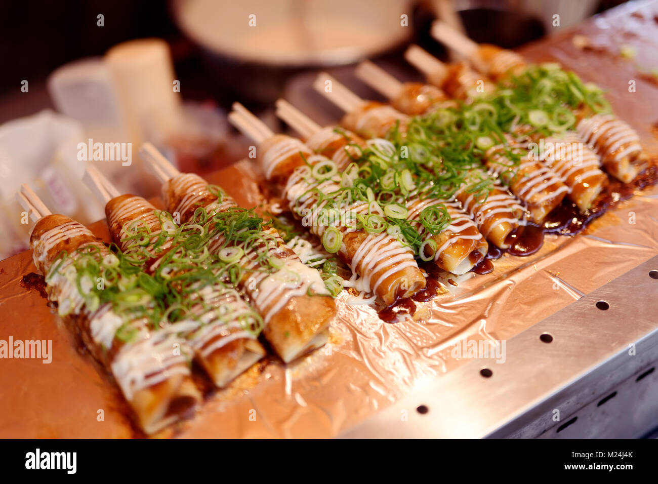 Okonomiyaki, Hashimaki laminés sur les baguettes, l'alimentation de rue japonais sur un étal de marché à Kyoto, Japon Banque D'Images