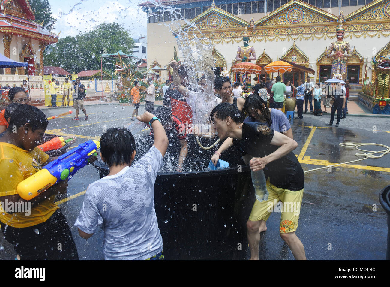 Les gens au festival de Songkran jetant de l'eau dans des seaux à l'autre d'un alrge reservoir d'eau, l'eau est gelée en mouvement Banque D'Images