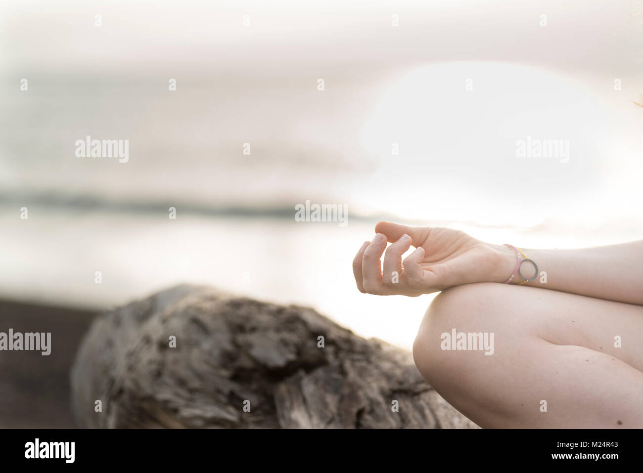 Méditer sur la plage avec le coucher du soleil dans l'arrière-plan Banque D'Images