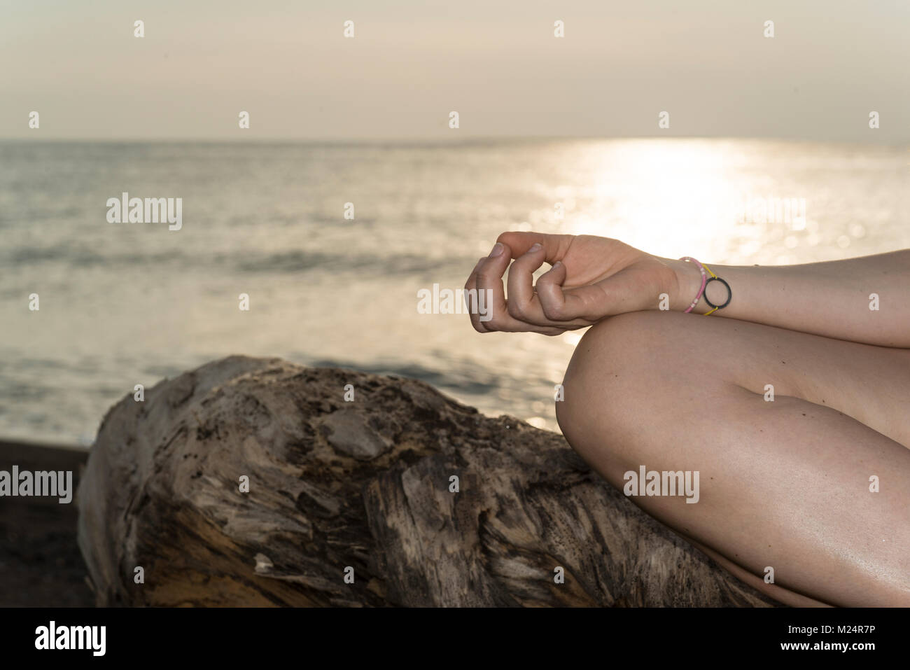 Méditer sur la plage avec le coucher du soleil dans l'arrière-plan Banque D'Images