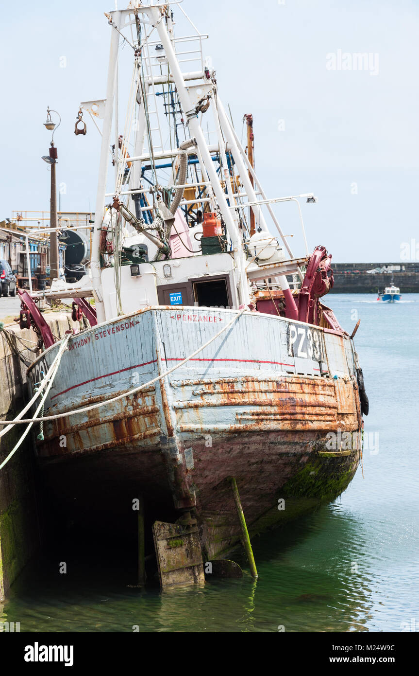 Bateau de pêche avec de la rouille, de la coque dans le port de Penzance, à marée basse. Cornwall, England, UK Banque D'Images