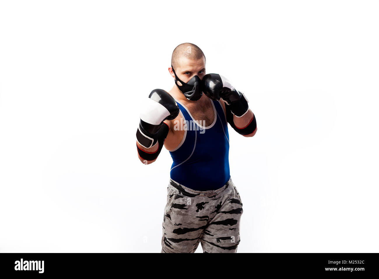 Jeune homme sportif en bleu-noir, masque de formation, en noir et blanc des gants de boxe et coudières noir sur blanc fond isolé case Banque D'Images